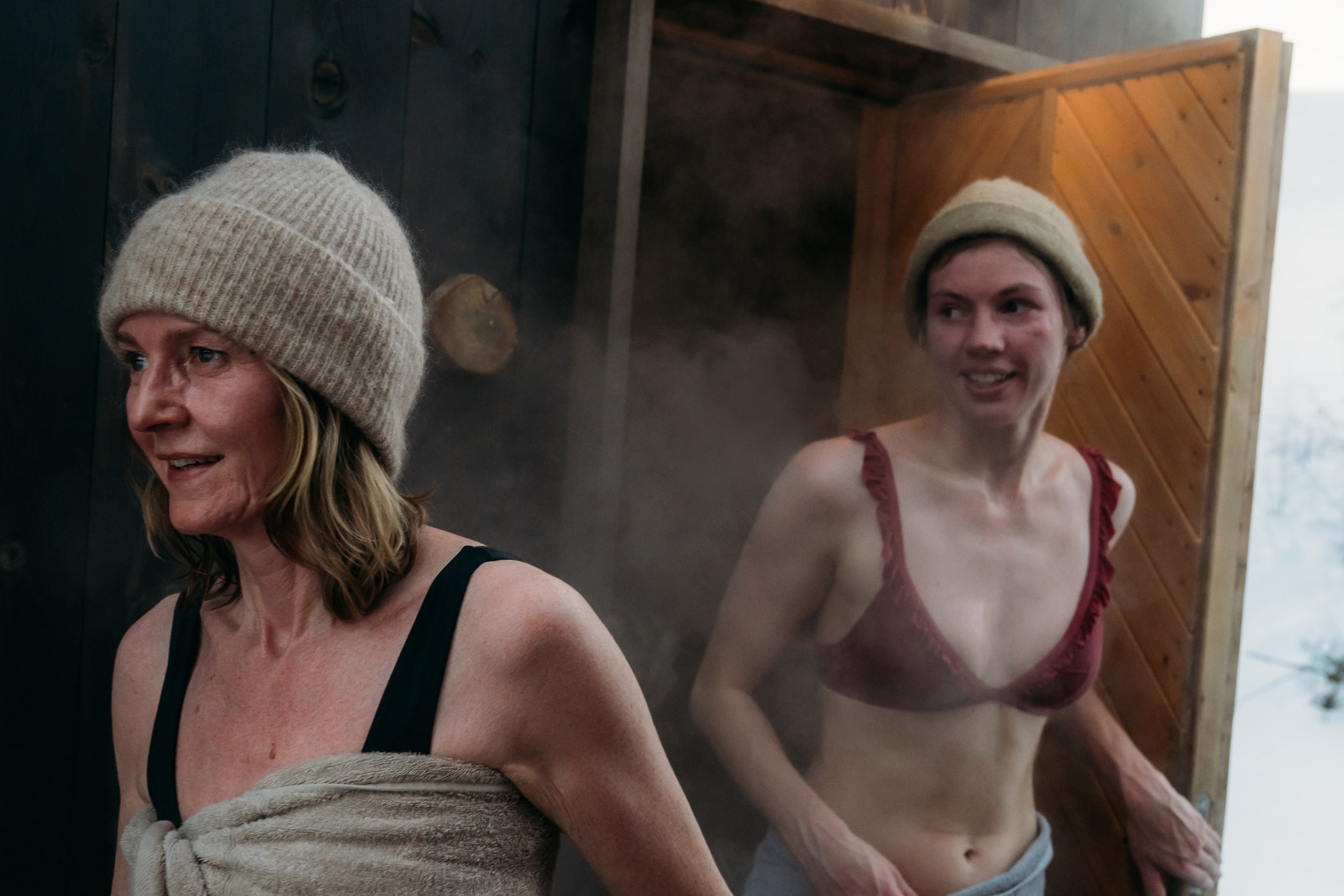 To damer som går ut av ei badstue med dampende kropper