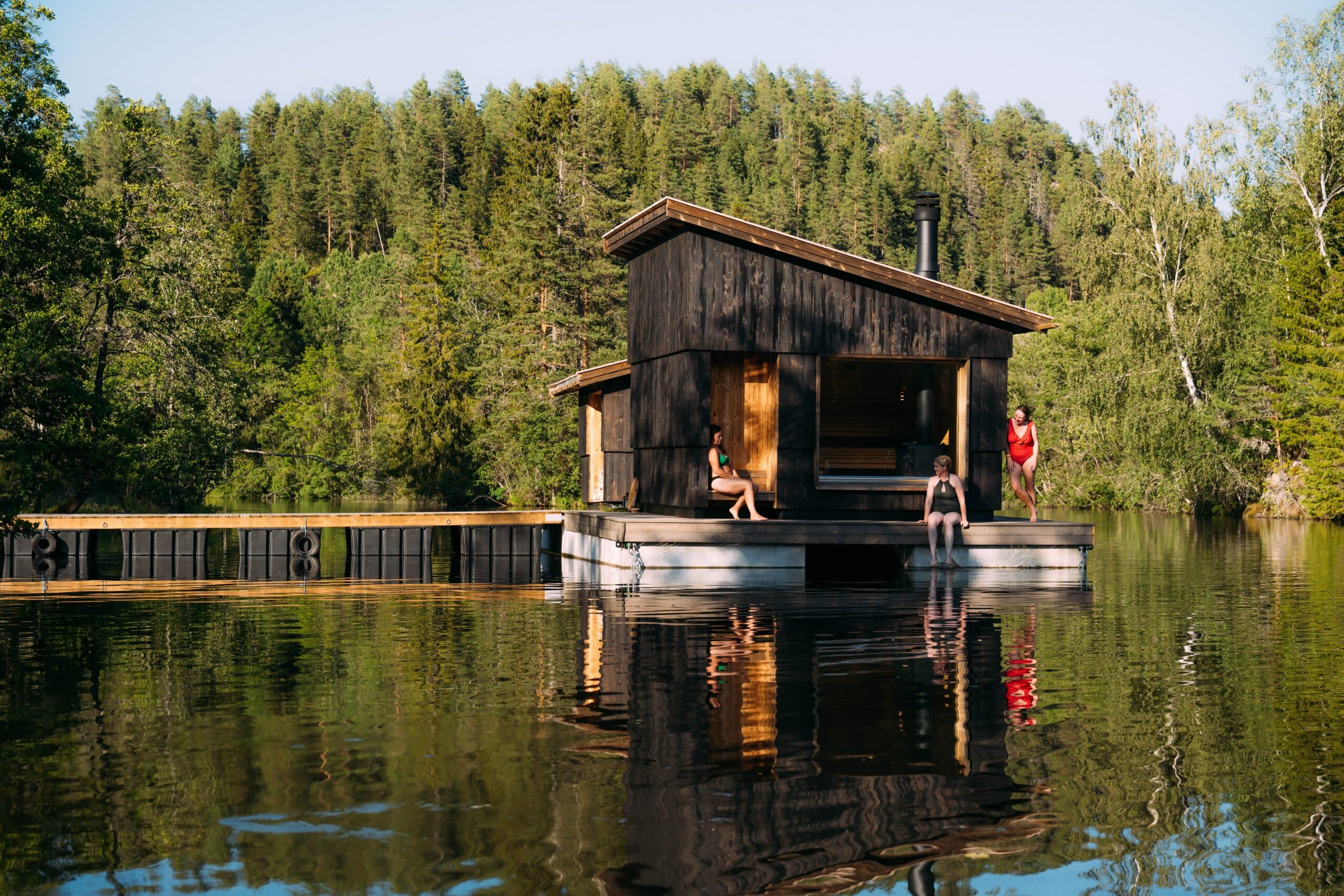Flytende sauna på Telemarkskanalen. 3 damer sittende på dekk.
