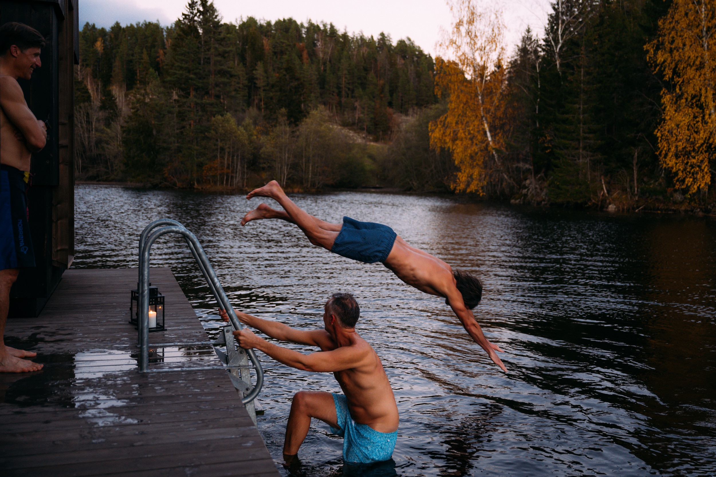 Tre menn som bader og stuper fra badstueflåte om høsten