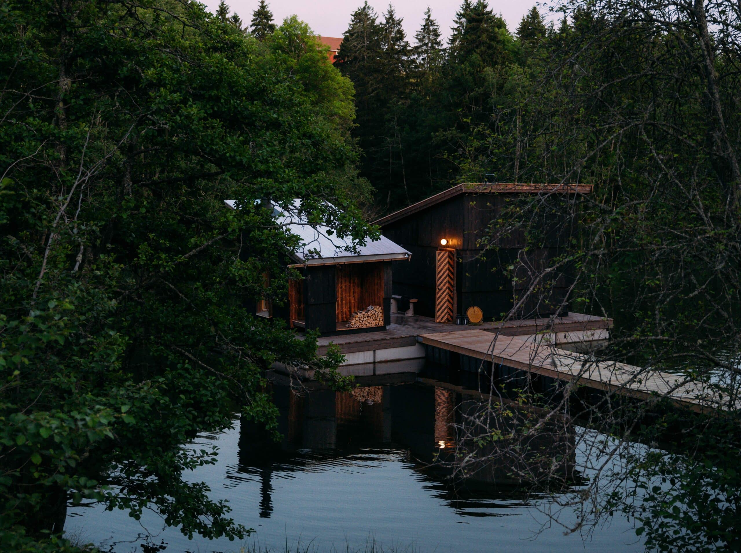Trolsk bilde av Skogens rom Sauna en sein sommerkveld - mørkegrønne trær, flytende sauna, refleksoner i vann