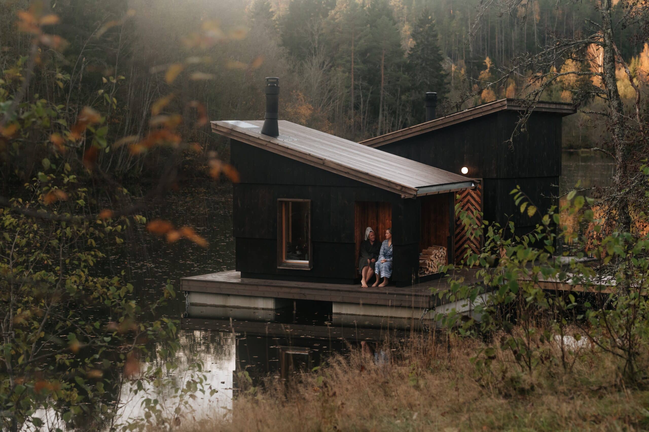 two women sitting on a dock by a lake