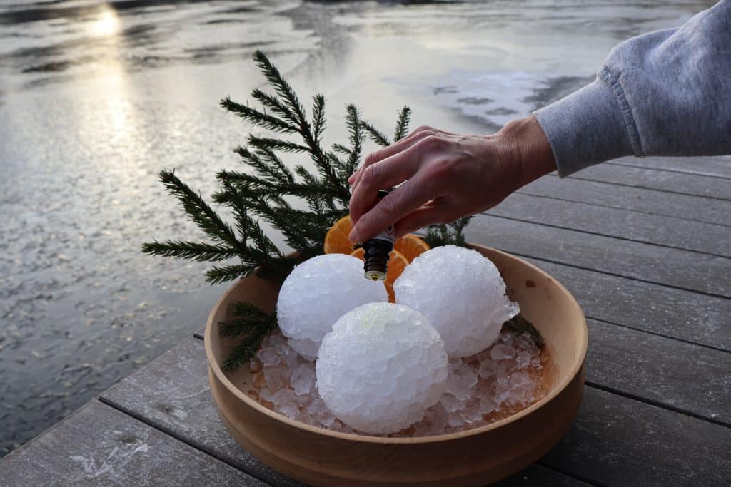 Hånd som drypper eteriske oljer over isballer til aufguss